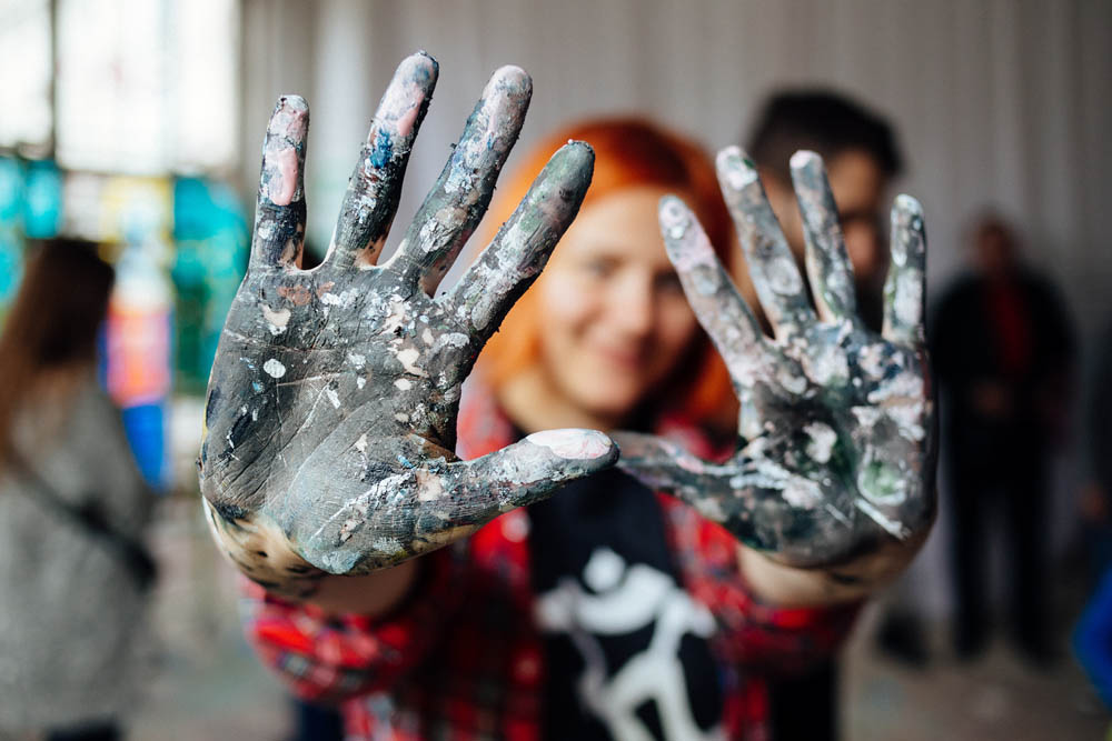 Young person showing hands covered with paint